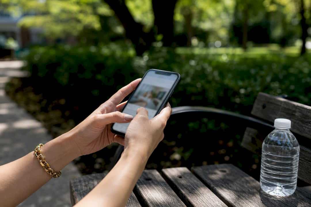 Hands holding phone showing property photos outdoors